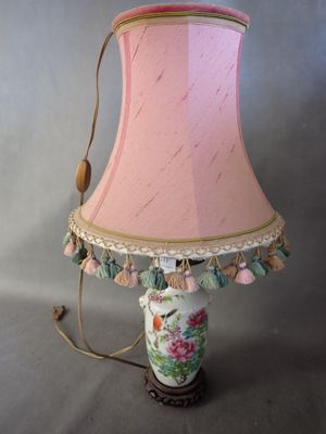une lampe posée sur une table, avec un abat-jour rose