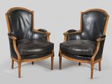 pair of black leather armchairs with carved wood arms