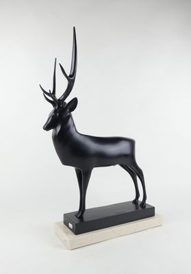 une sculpture noire représentant un cerf, posée sur un socle en marbre