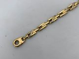 a close up of a gold bracelet on a white surface