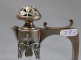 a silver tea pot with a butterfly decoration on it