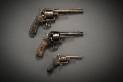 three old revolvers are sitting on a table with a black background