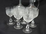 five wine glasses and a decanter on a table