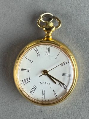 a gold pocket watch with roman numerals on it
