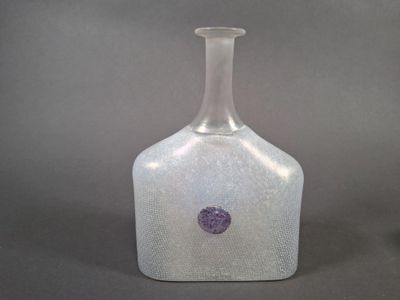 une bouteille en verre avec un point violet dessus
