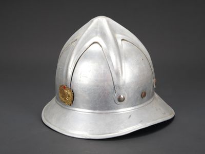 un vieux casque de pompier en argent orné d'un insigne doré