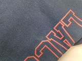 a close up of a t - shirt with a red logo on it