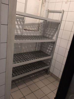 a white tiled bathroom with shelves and tiled floor