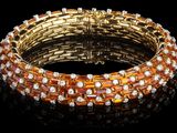 un bracelet en or orné de pierres orange et blanches sur fond noir