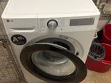a washing machine sitting on the floor next to a trash can