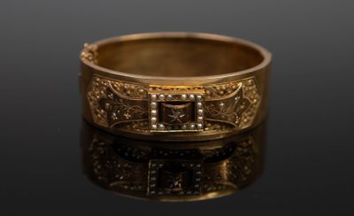 une image montrant un gros plan d'une bague en or posée sur une surface noire