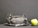 a statue of a woman and an apple sitting on a table