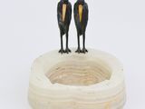 two birds that are standing on top of a wooden bowl