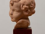 sculpture of a child ' s head on a wooden base