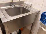 a stainless steel sink in the corner of a bathroom