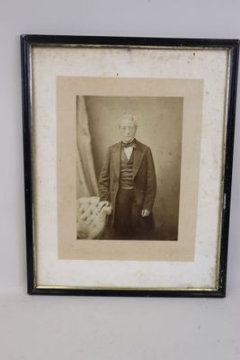une vieille photo d'un homme en costume et nœud papillon, dans un cadre noir