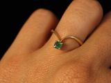 a close up of a person ' s hand with a gold ring with a green stone