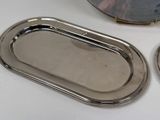 two silver trays sitting on a table next to a mirror