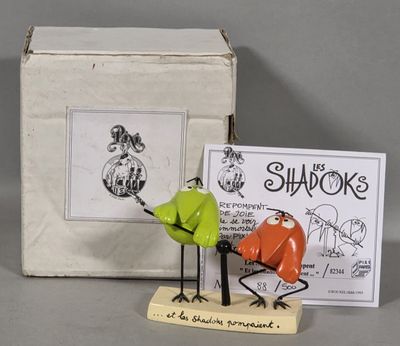 two figurines of birds that are standing next to a box