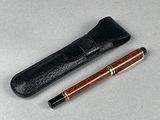 une image représentant un stylo et un étui en cuir posés sur une table