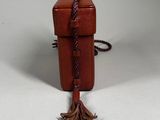a small brown box with a tassel hanging from it