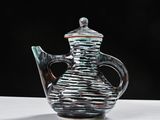 a glass teapot sitting on a table with a black background