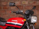 a red and black motorcycle parked in front of a brick wall