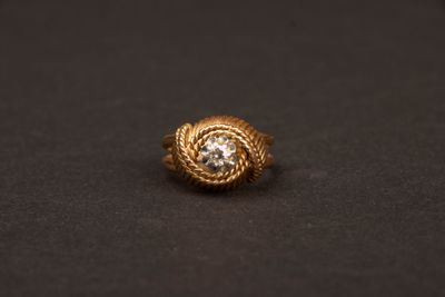 une bague en or avec un diamant au centre, sur un fond noir