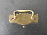 an old brass handle on a black suitcase with a bird on it