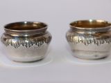 deux tasses en argent posées l'une à côté de l'autre sur une table