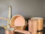 a lot of copper pots and pans on a table