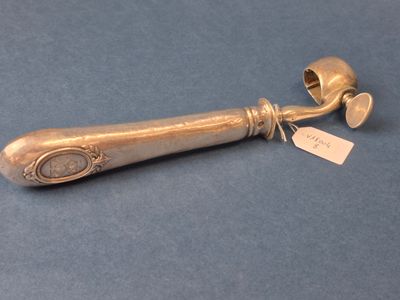 une brosse à dents ancienne en argent posée sur un fond bleu, avec une étiquette de prix