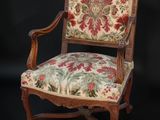 une chaise en bois avec une assise et des accoudoirs rembourrés d'un motif floral