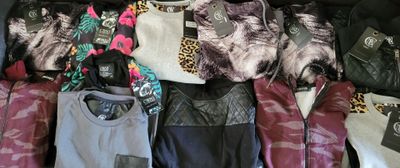 many different types of jackets and pants on a bed