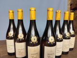 six bottles of wine are lined up on a wooden table