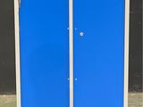 une armoire bleue et blanche à deux portes, montée sur roulettes, devant un mur noir