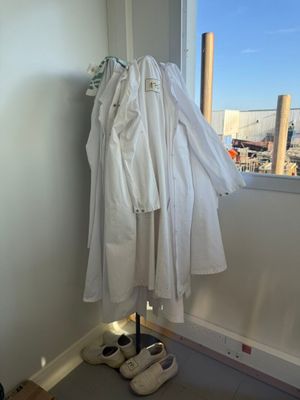 a white shirt hanging on a clothes rack next to a pair of white shoes