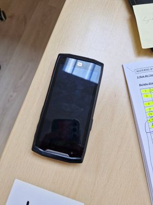 un téléphone portable posé sur un bureau, à côté d'une feuille de papier