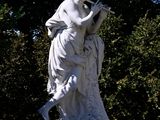 a statue of a woman sitting on a bench in a park