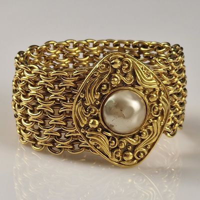 an image of a close up of a gold bracelet with a pearl in it