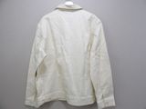 a white jacket hanging on a hanger against a wall