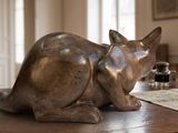 une statue représentant un chat assis sur une table en bois