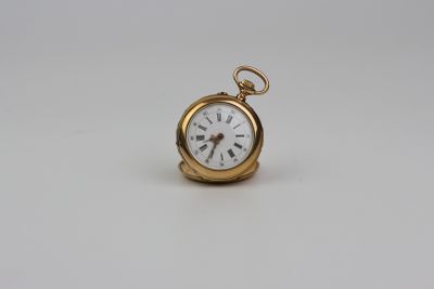 une montre de poche en or avec un cadran blanc sur une surface blanche