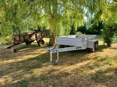 a white trailer parked under a tree in a field