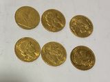 six gold coins are arranged in a row on a white surface