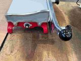 a red and silver stove sitting on a wooden table