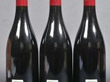 three bottles of red wine are lined up on a table
