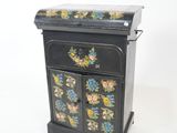 a small black cabinet with a floral design on it