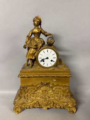 a gold clock with a woman holding a bird on top of it