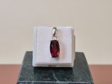 a close up of a ring with a red stone on top of a marble block